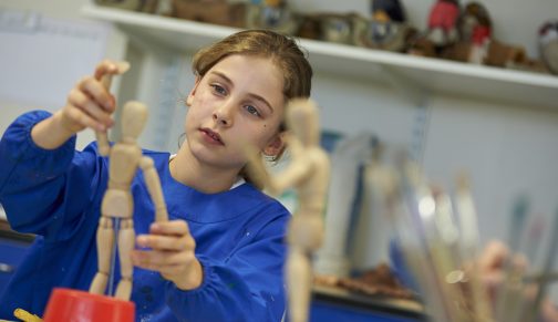 girl playing with a wooden doll