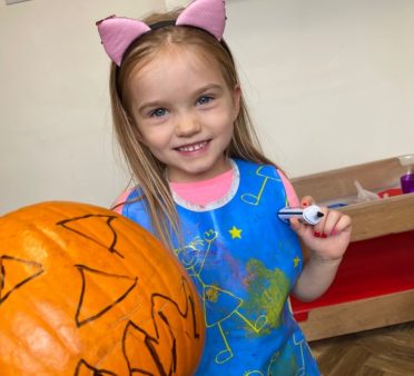 girl drawing on a pumpkin