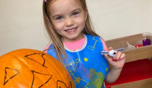girl drawing on a pumpkin