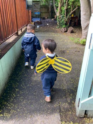 Young boy and girl walking to their nursery classroom. The girl is wearing bee wings